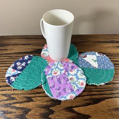 a cup and some coasters sitting on a table with a mug in the middle