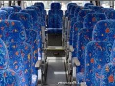 the inside of an empty bus with blue seats and red flowers on it's seat covers