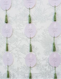 wedding table numbers with tassels and flowers on the wall in front of them