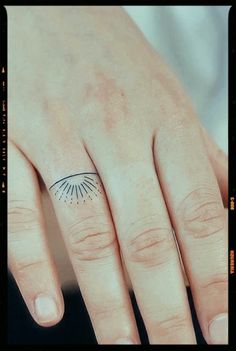 a woman's hand with a small sun tattoo on her left thumb and ring finger