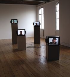 three different sized televisions are on display in an empty room with wooden floors and windows