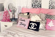 a bed topped with lots of pillows next to a white dresser and pink christmas tree