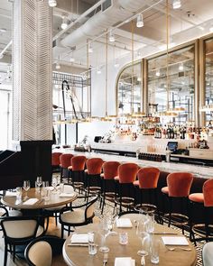 an empty restaurant with tables and chairs in front of the bar, filled with wine glasses