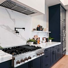 a kitchen with marble counter tops and blue cabinets, along with an island stovetop