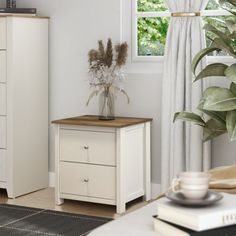 a bedroom with a bed, dresser and plant in the corner on top of it