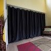 a living room with black curtains and a red rug on the floor next to a chair