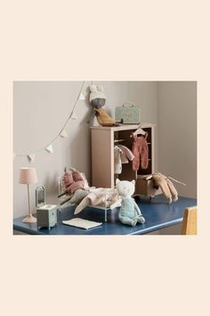 stuffed animals are sitting on a blue table in front of a bookcase and lamp