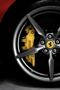 the front wheel of a red sports car with yellow brake pads