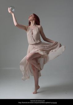 a woman in a dress holding a frisbee and looking up into the sky