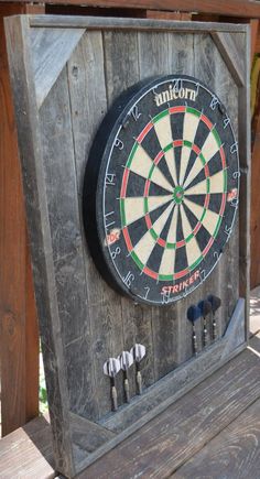 a dart board mounted to the side of a wooden fence with darts in it and four darts on each side