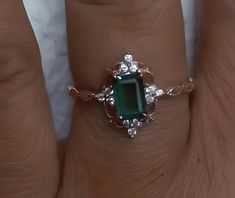 a woman's hand with a ring on it and an emerald stone in the middle