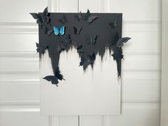 a black and white painting with blue butterflies on it's side, in front of a door