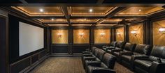 an empty theater room with black leather seats and gold wallpapered walls, along with a projector screen