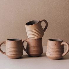 three coffee mugs stacked on top of each other in front of a beige wall