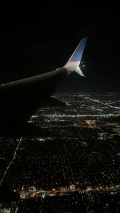 the wing of an airplane flying over a city at night