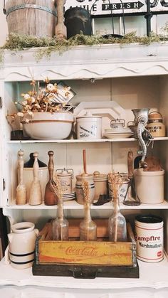 an old fashioned kitchen cabinet filled with dishes and utensils on top of it