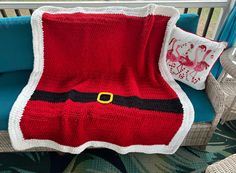 a red and white blanket sitting on top of a chair next to a blue cushion