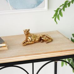 a small gold leopard figurine sitting on top of a table next to a book