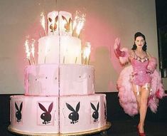 a woman in pink is standing next to a cake