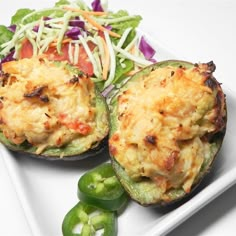 two stuffed zucchini halves on a white plate with green peppers and sprouts