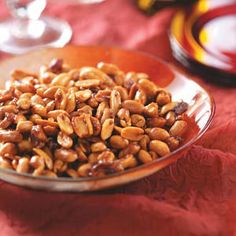 a bowl filled with nuts sitting on top of a red table cloth next to other plates