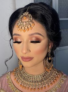 a woman with makeup and jewelry on her face, looking down at the camera while she is