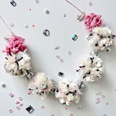 the necklace is decorated with pink flowers and silver sequins on a white background