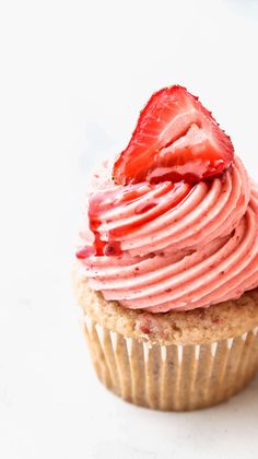 a strawberry cupcake with frosting and strawberries on top, ready to be eaten