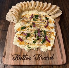 a wooden cutting board topped with a pizza covered in cheese and vegtables