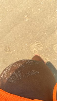 someone is laying down on the beach with their feet in the sand and one foot sticking out