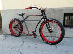 a bike with red rims is parked on the sidewalk