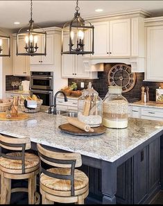 a large kitchen island with stools and lights hanging from it's ceiling above it