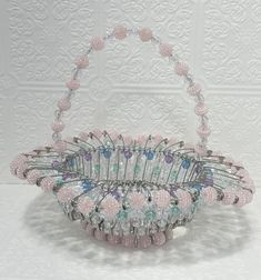 a pink and silver basket sitting on top of a white table next to a wall