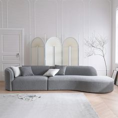 a large gray couch sitting on top of a wooden floor next to a white rug