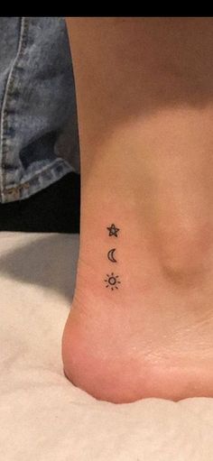 a woman's foot with three small stars and moon tattoos on the side of her ankle