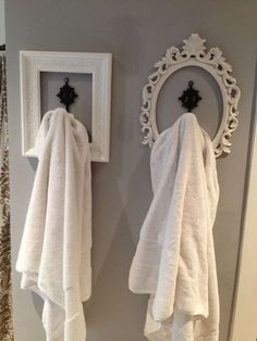 two white towels hanging on the wall next to a mirror