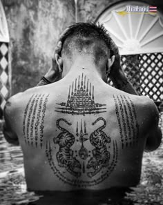 a man with tattoos on his back sitting in the water