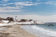 the beach is covered in snow and has a light house on it's side