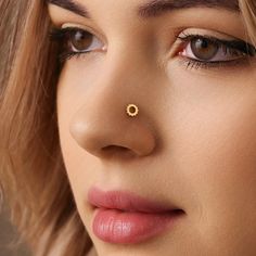 a close up of a woman's nose with a gold nose ring on it