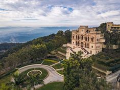 an aerial view of a large mansion on top of a hill with trees and bushes