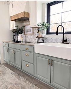 a kitchen with gray cabinets and white counter tops, black faucet above the sink