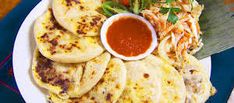 a white plate topped with tortillas and cole slaw next to a bowl of sauce