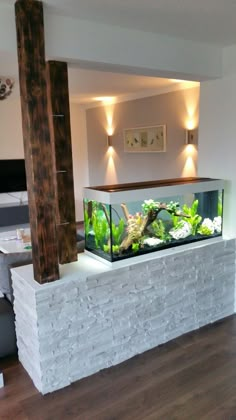 a fish tank sitting on top of a white brick wall next to a wooden floor