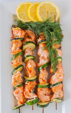 grilled shrimp and zucchini skewers on a white platter with lemon wedges