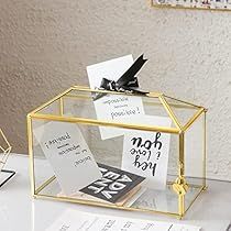 a glass box with some notes in it sitting on a table next to a pen and paper