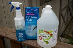 several cleaning products are sitting on a wooden fence rail, including soap, cleaner and deodorant