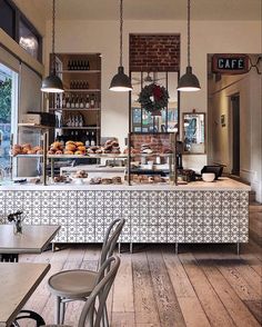 the interior of a coffee shop with tables and chairs in front of it, along with an assortment of pastries on display