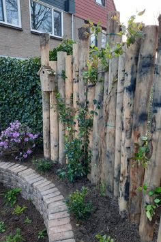 a wooden fence made out of logs with plants growing on it