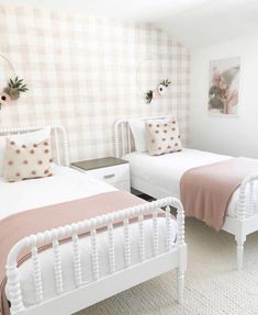 two white beds in a room with pink and white decor on the wall behind them