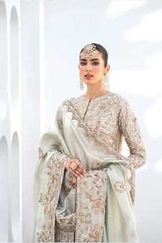 White Lehenga Kameez Pakistani Wedding Dresses come in a long kameez in raw silk with an embroidered bridal dress with heavy work done on it paired with a lehenga and tissue embellished dupatta. White Lehenga Kameez: Pakistani wedding dresses are cut from the finest gold tissue, this flared front open shirt is adorned with a floral trellis and intricately embellished with pearls, silk thread work, crystals, and a shimmering sequence layered under a floor-length shirt is undeniably charming. Whit Pakistani Mexican Wedding, Lehenga Kameez, Nikkah Decor, Silk Kameez, Work Crystals, Long Kameez, Kameez Lehenga, Feminine Inspiration, Pakistani Bridal Dress